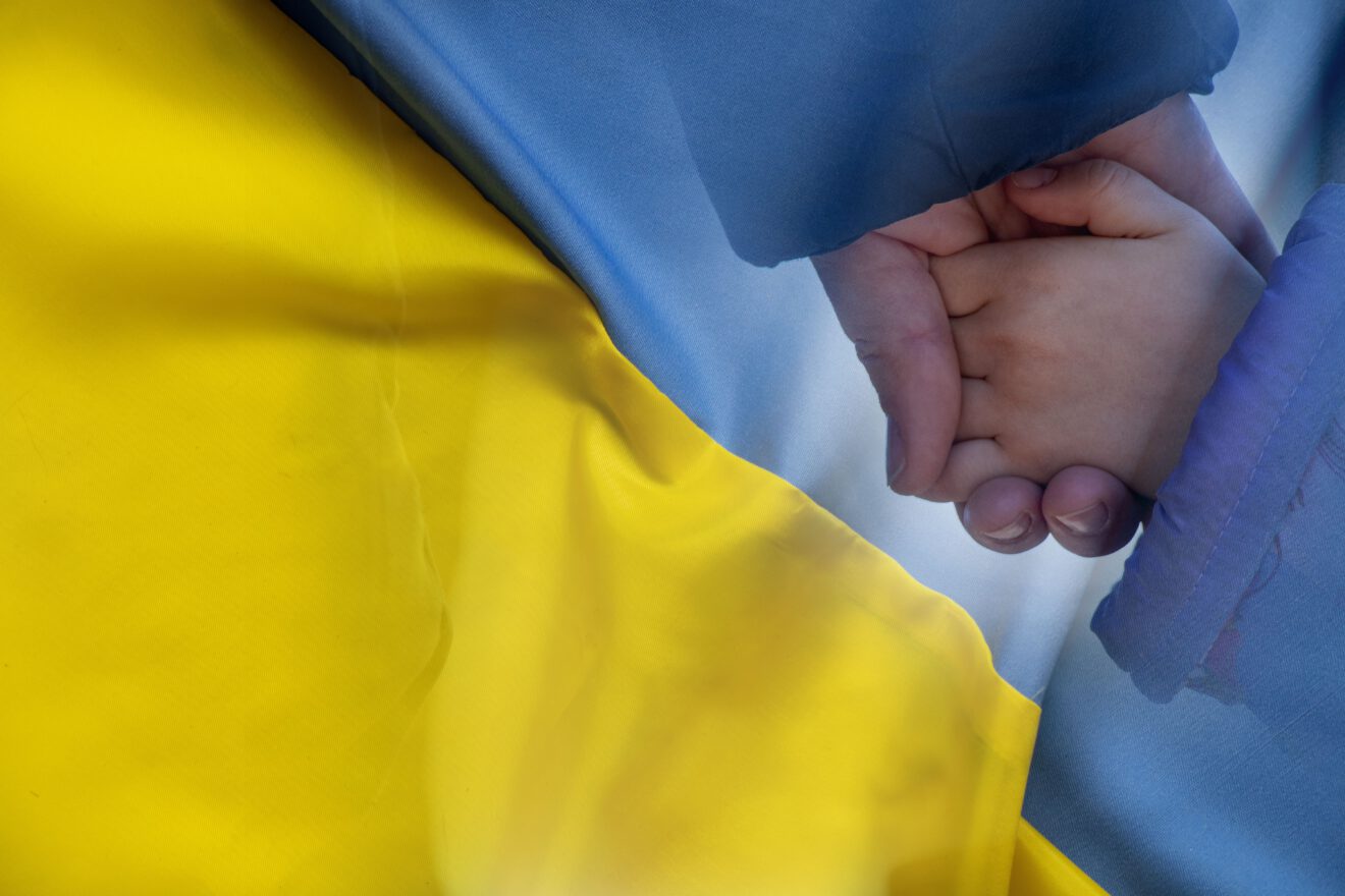 Mother holds a little girl by the hand against the background of the national flag of Ukraine yellow-blue. Peace in Ukraine, stop the war